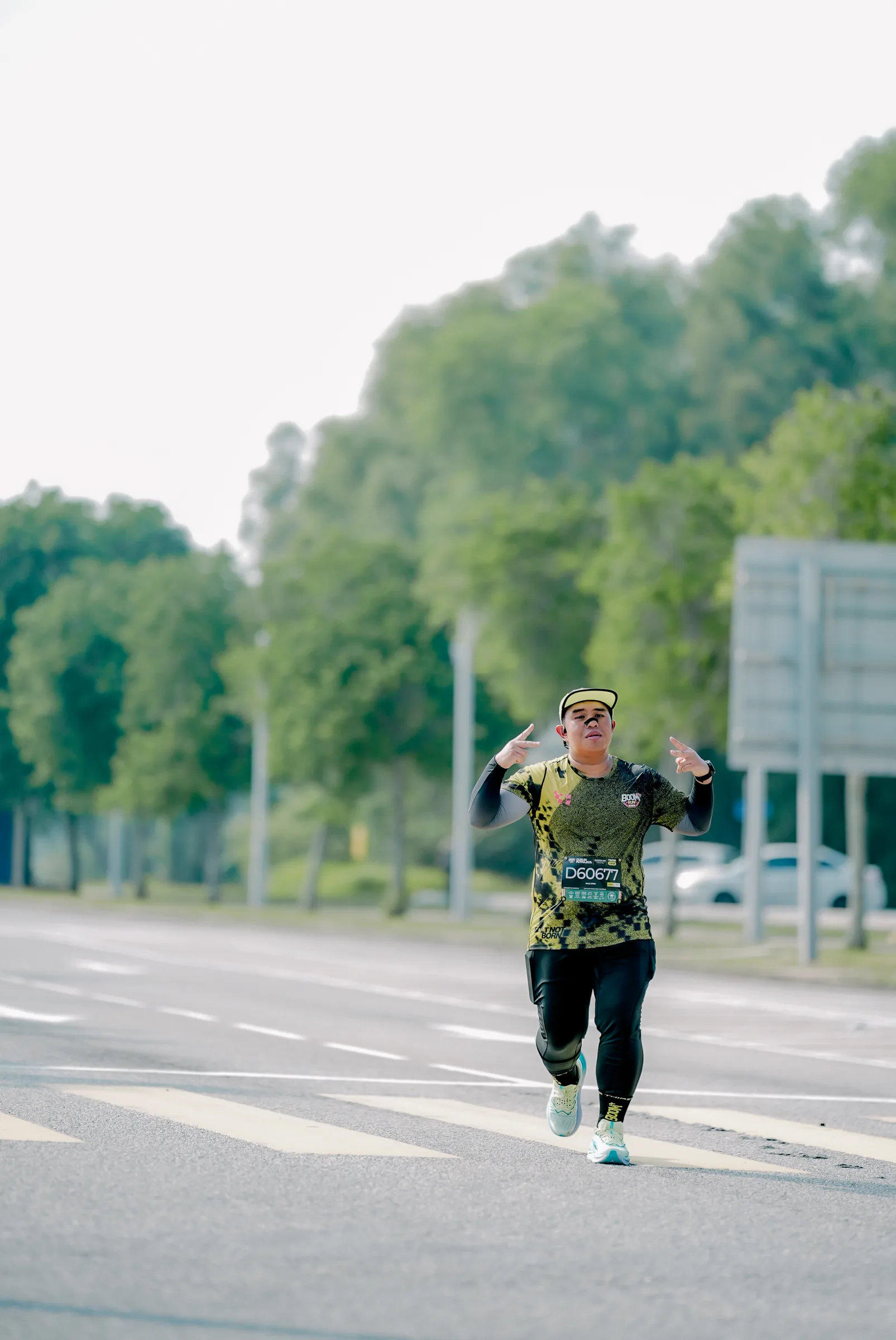 Razeen running toward the camera, arms raised, during a road race